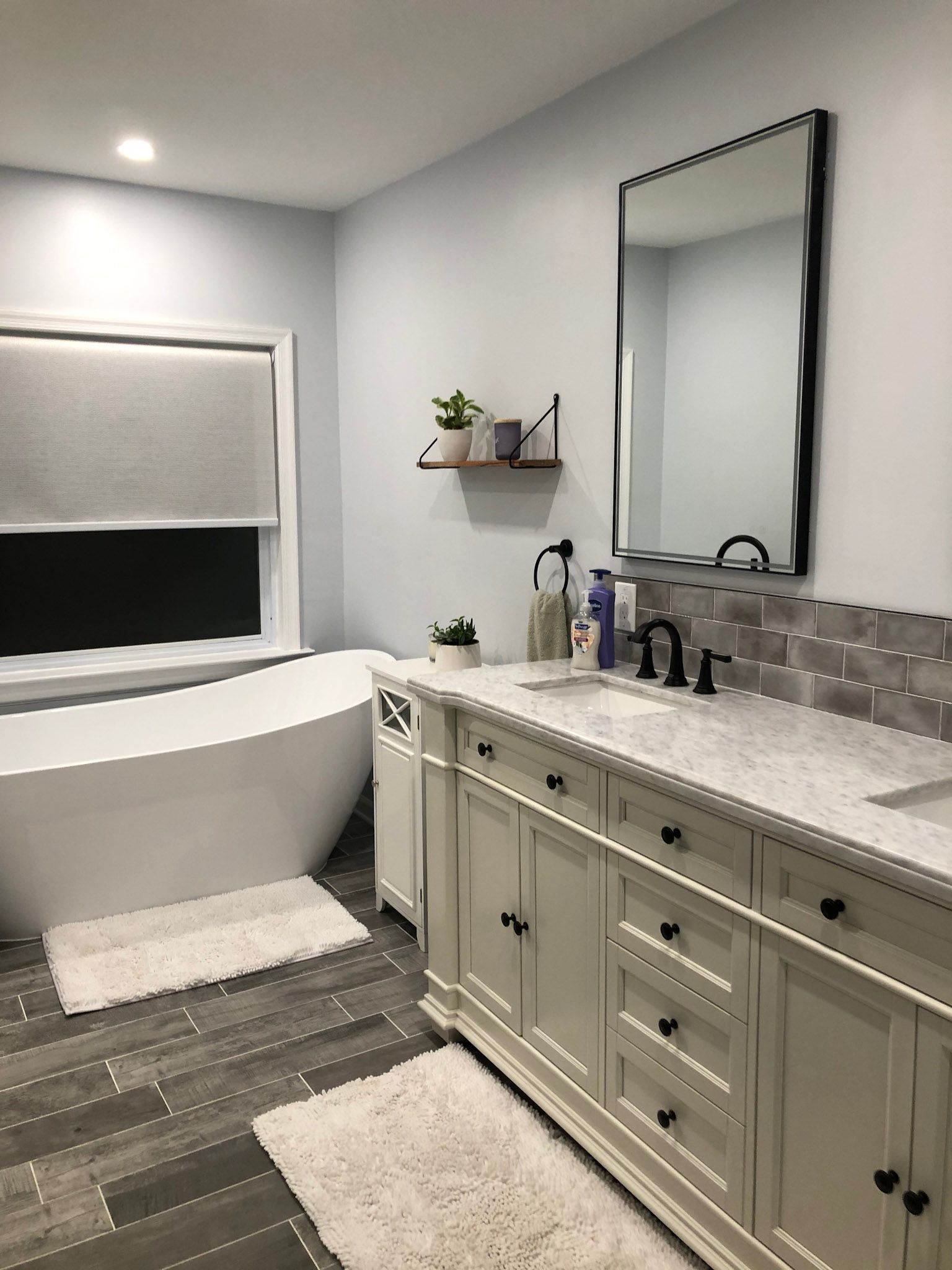 a bathroom with a tub , sink , mirror and cabinets .