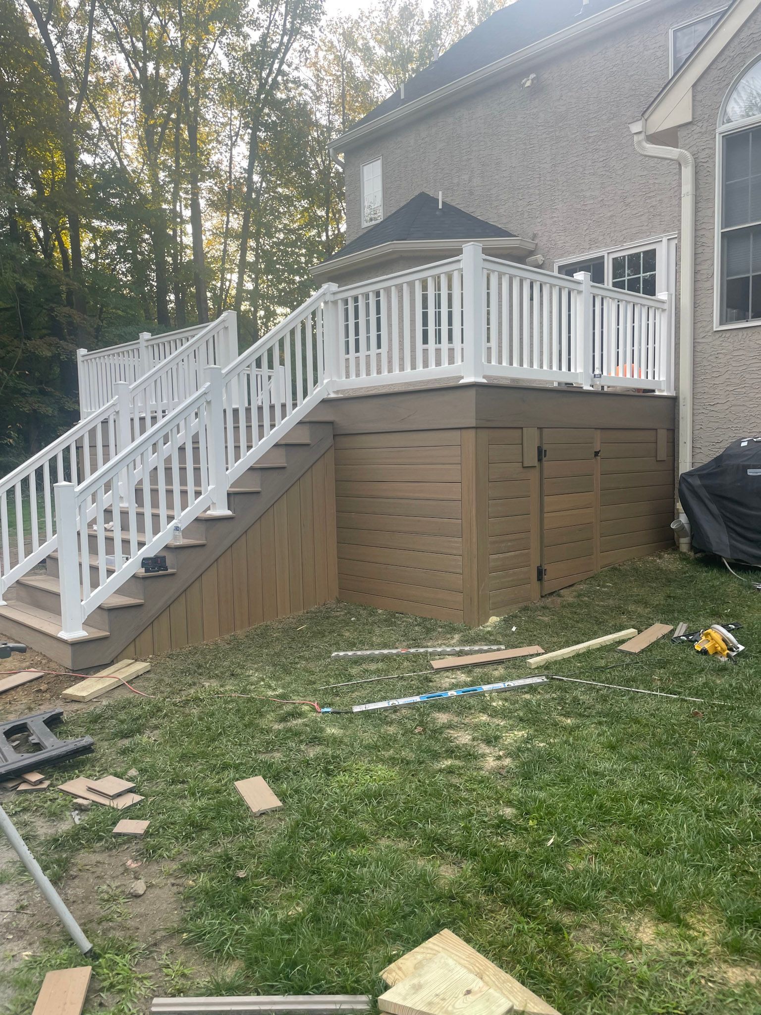 a deck with stairs and a white railing is being built in the backyard of a house .