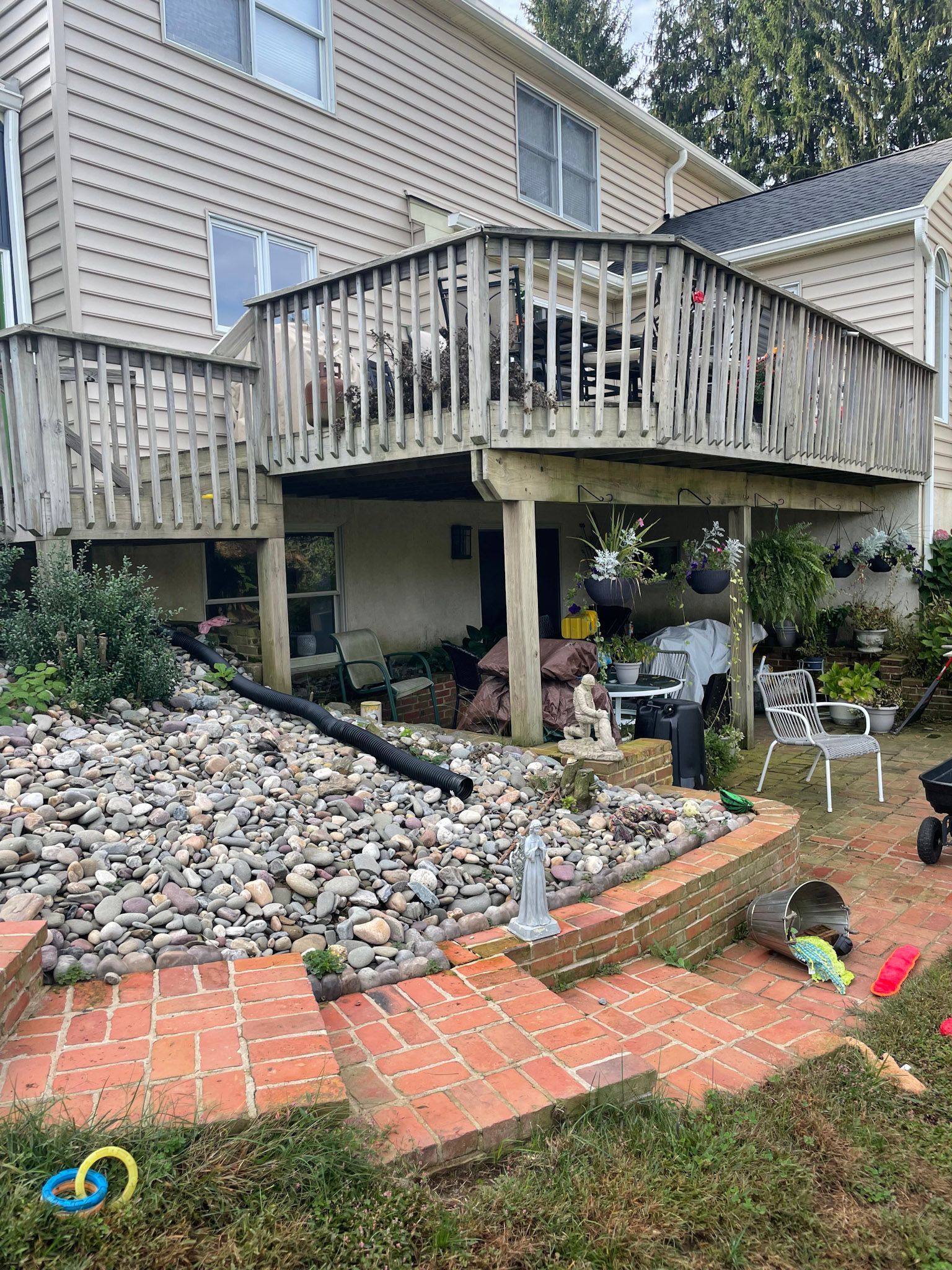 a large wooden deck is sitting on top of a rocky hill next to a house .