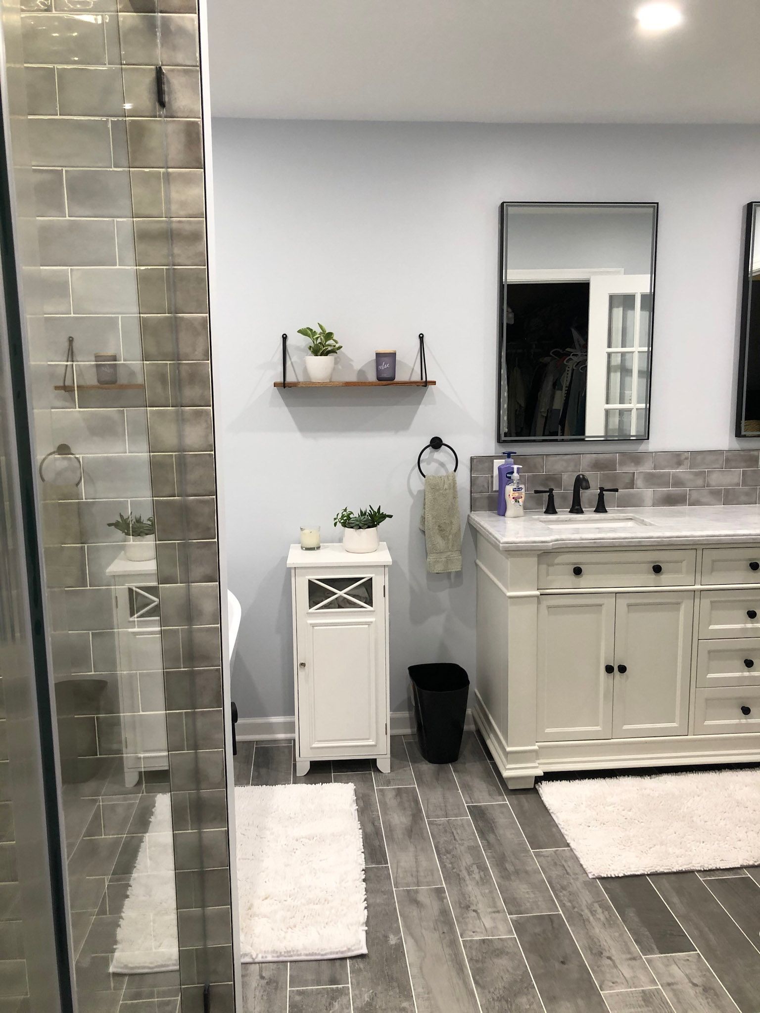 a bathroom with two sinks , a mirror and a walk in shower .
