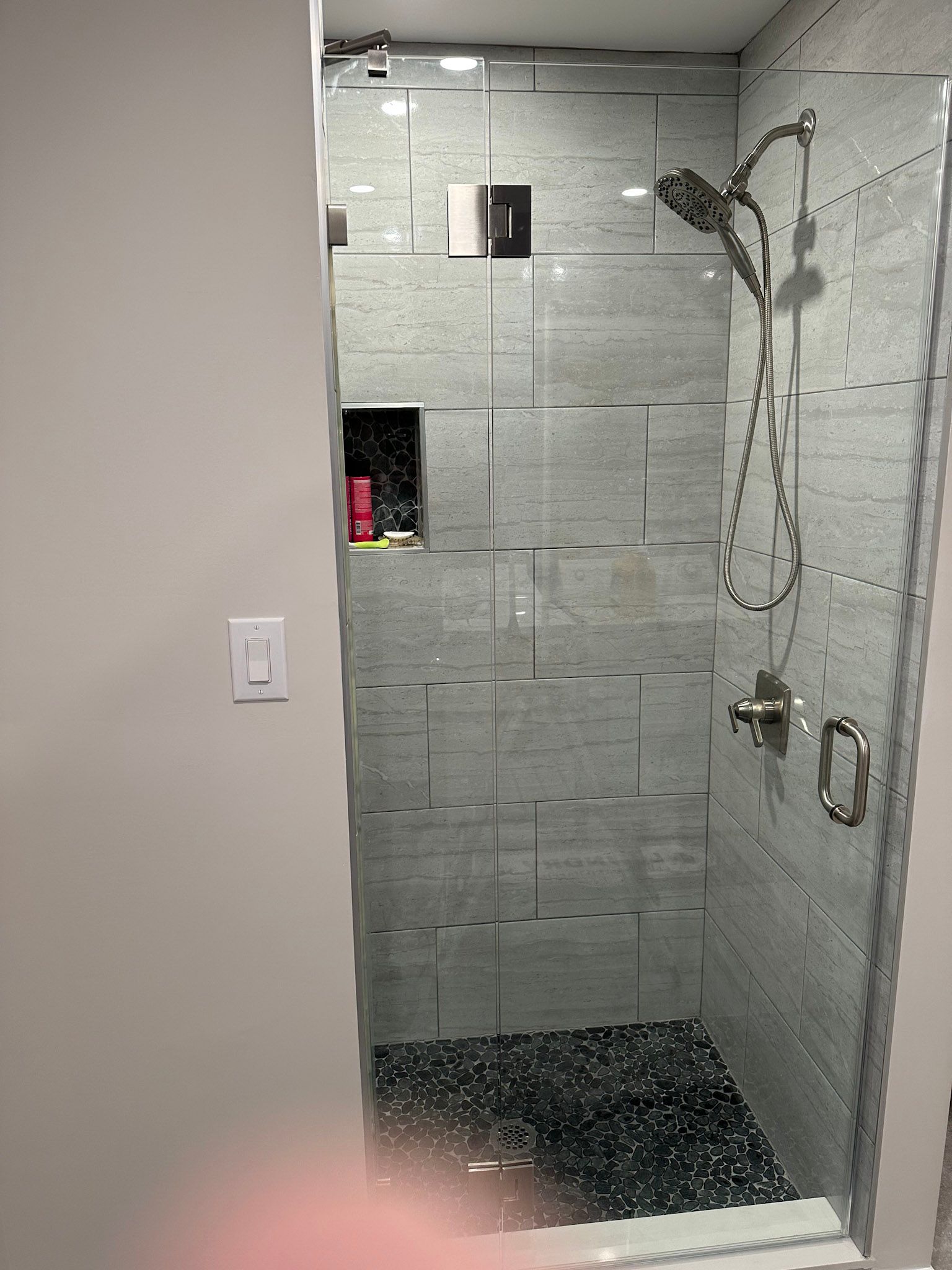 a bathroom with a walk in shower with a glass door .