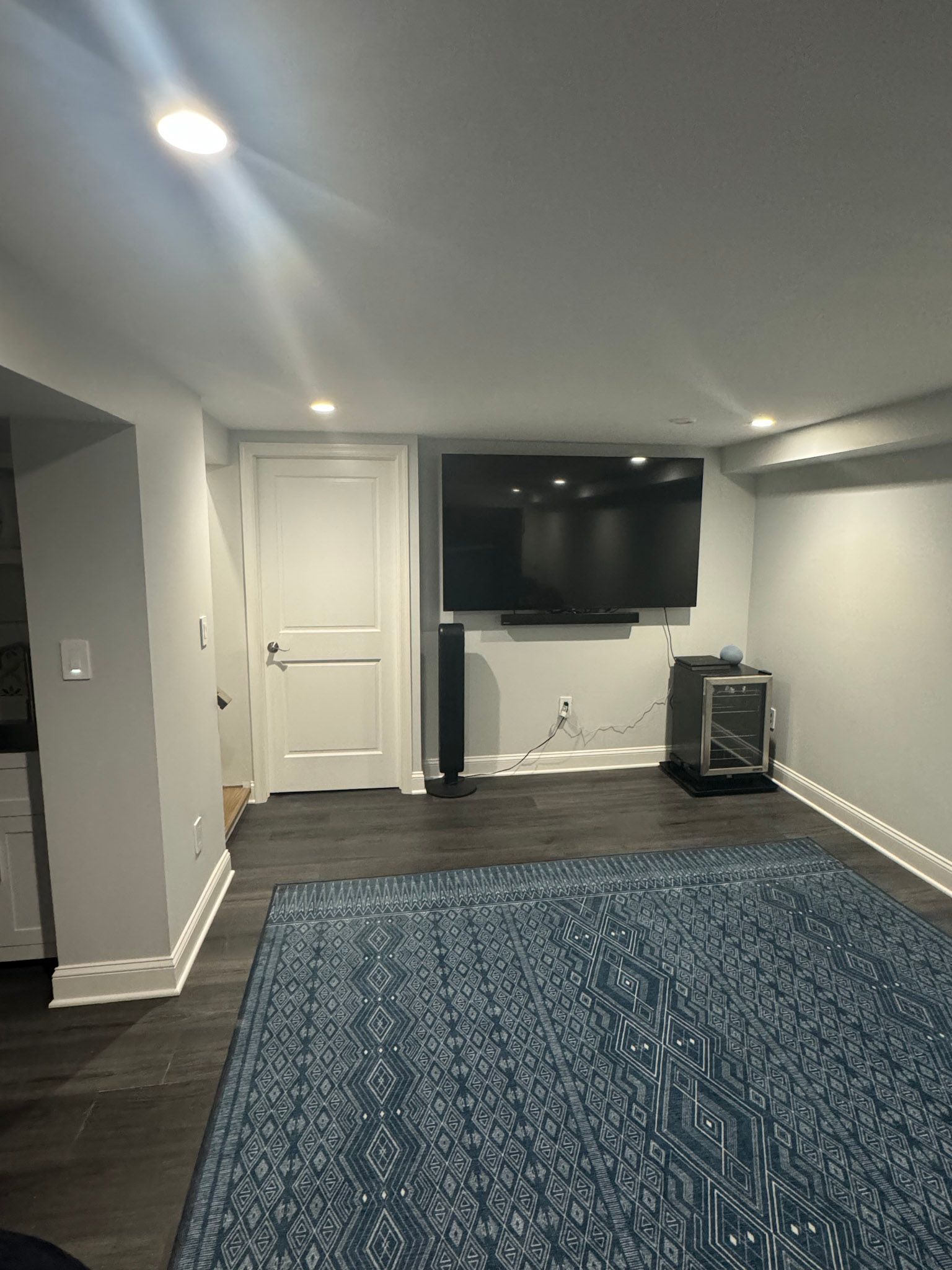 a living room with a large flat screen tv and a blue rug .