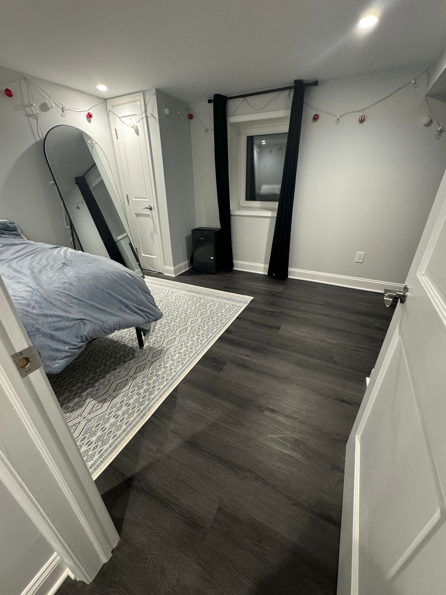 a bedroom with a bed , mirror and rug .