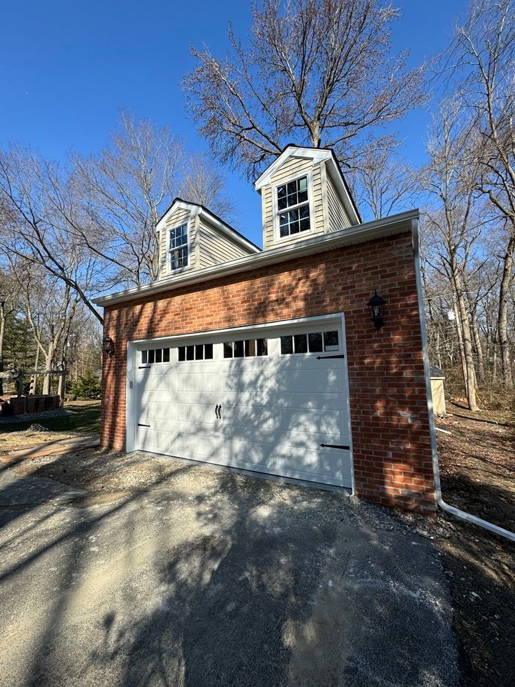 a large white garage door is sitting in front of a brick house .