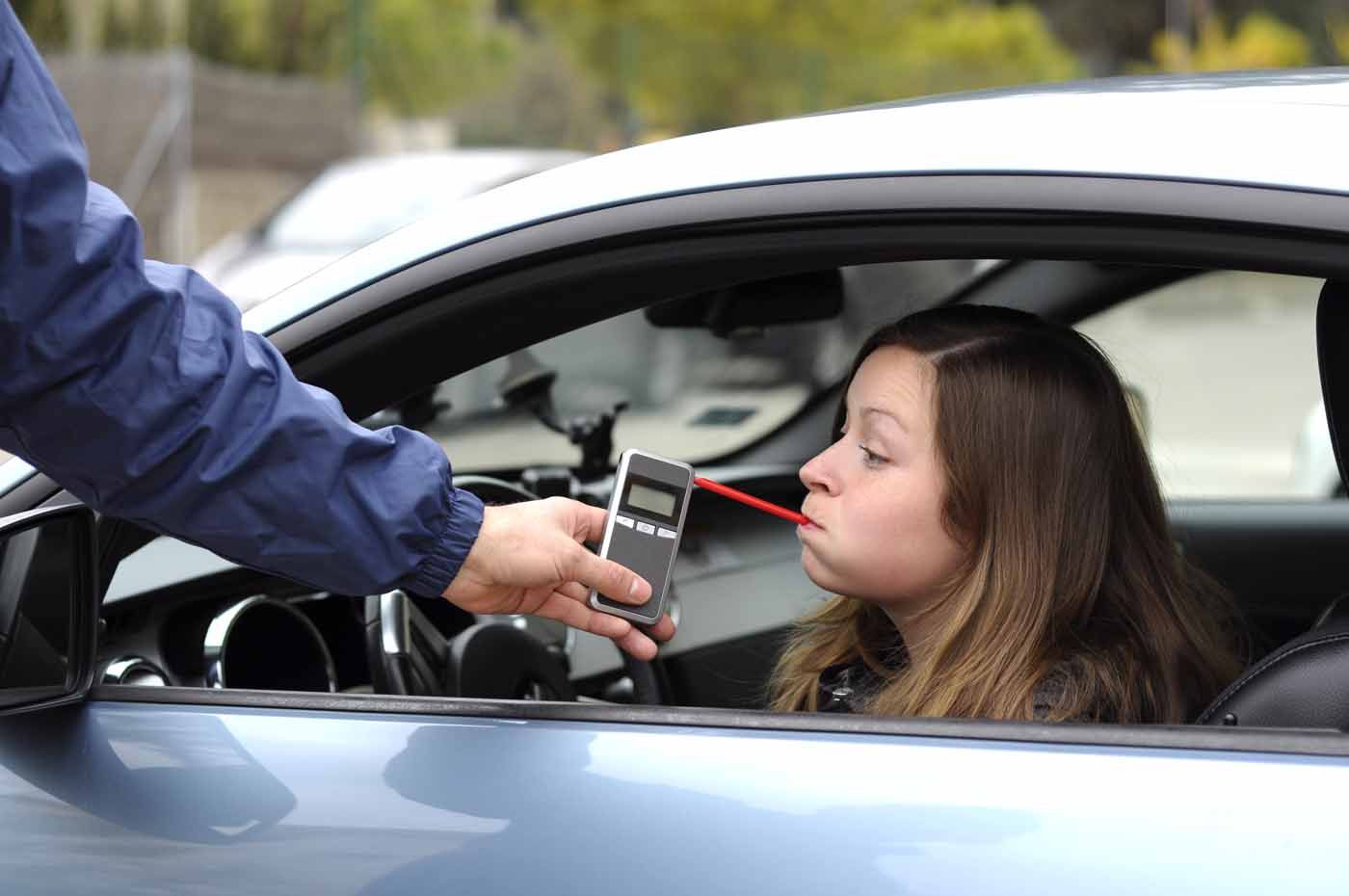 A woman in a car is being tested for alcohol by a police officer.