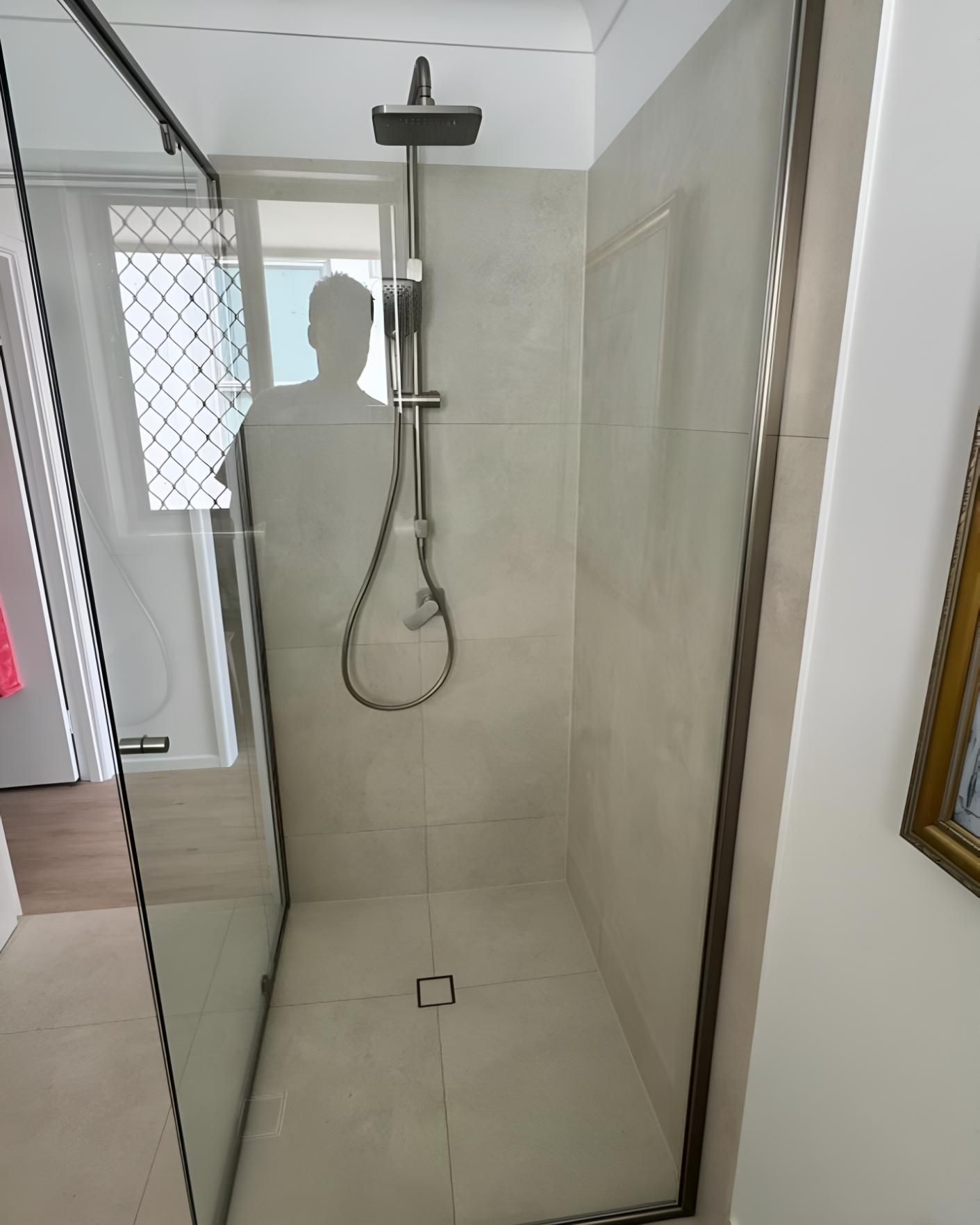 Man is Standing in a Shower With a Shower Head — Luke Barry Plumbing in Labrador, QLD