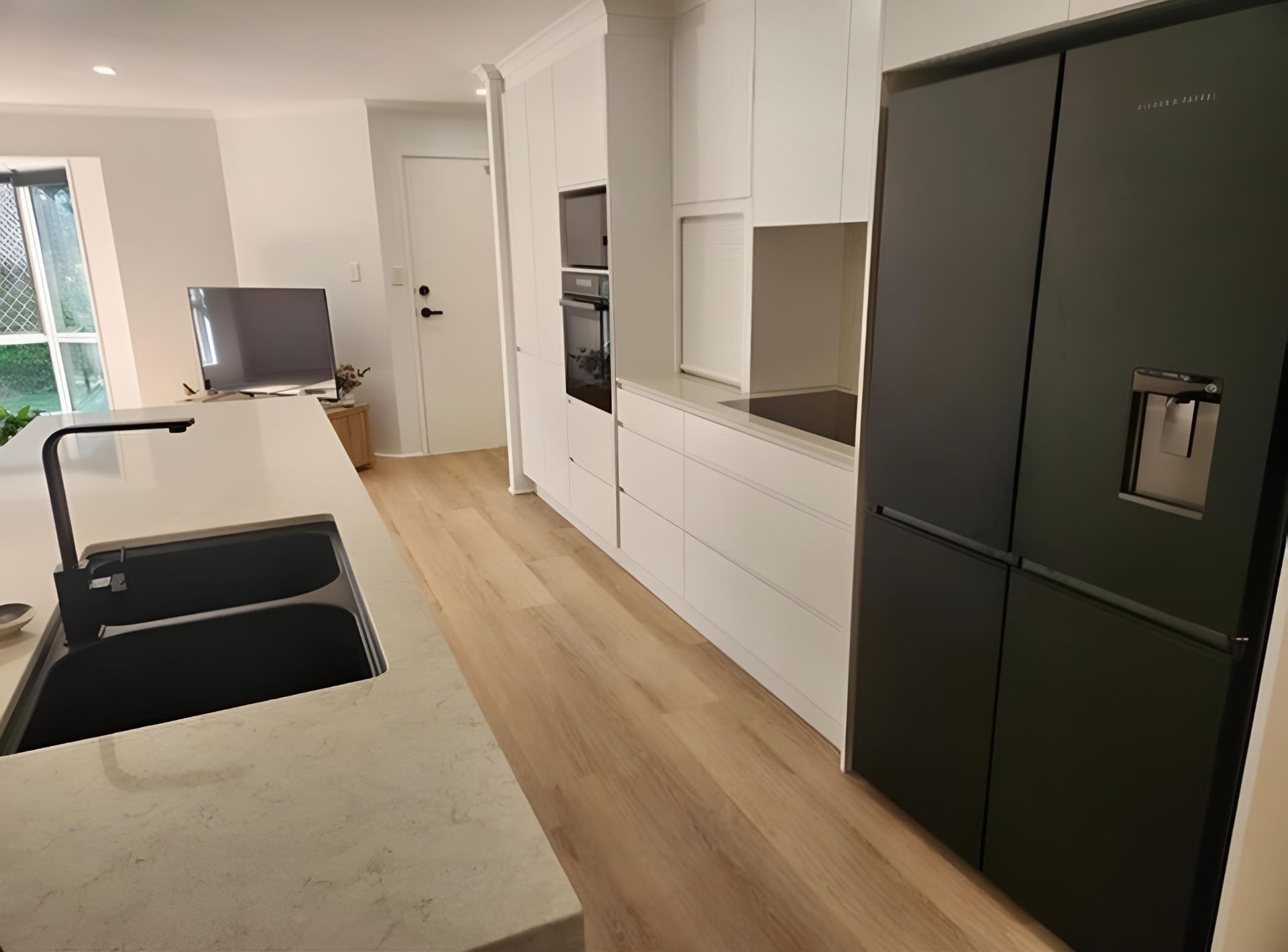 Kitchen With a Black Refrigerator and a Sink — Luke Barry Plumbing in Upper Coomera, QLD