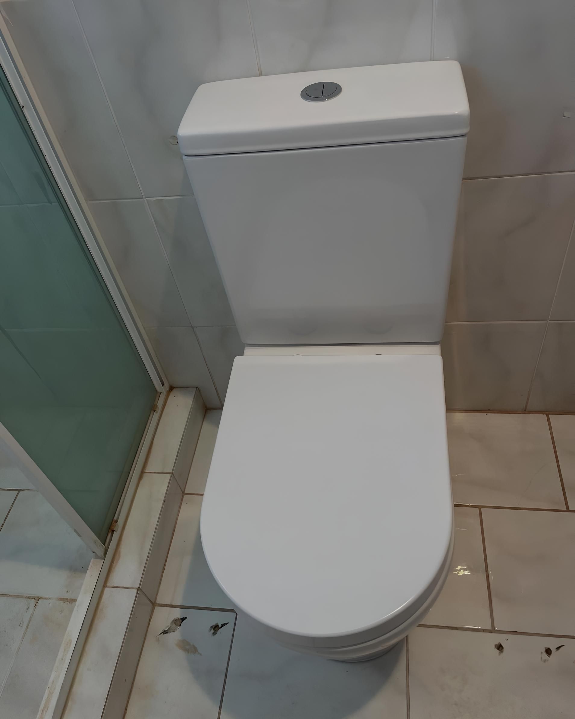 White Toilet is Sitting on a Tiled Floor in a Bathroom — Luke Barry Plumbing in Ormeau, QLD