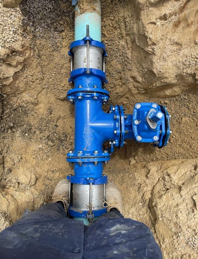 Person is Standing Next to a Blue Pipe in the Dirt — Luke Barry Plumbing in Robina, QLD