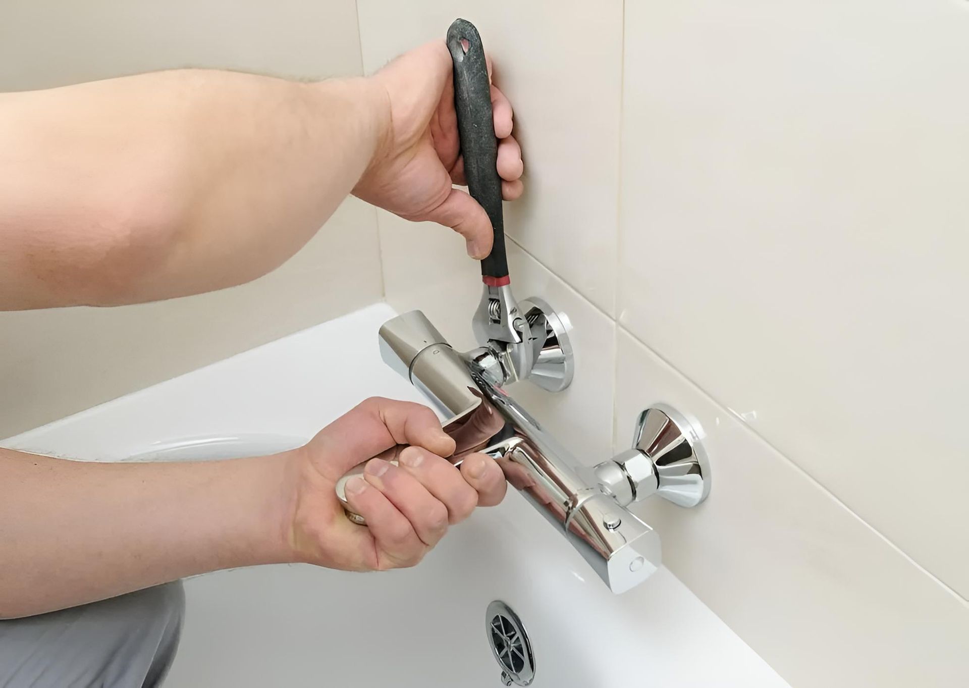 Person is Fixing a Bathtub Faucet With a Wrench — Luke Barry Plumbing in Mudgeeraba, QLD