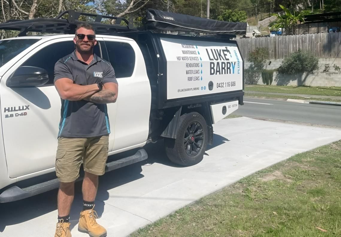 Man is Standing in Front of a Truck With His Arms Crossed — Luke Barry Plumbing in Mudgeeraba, QLD