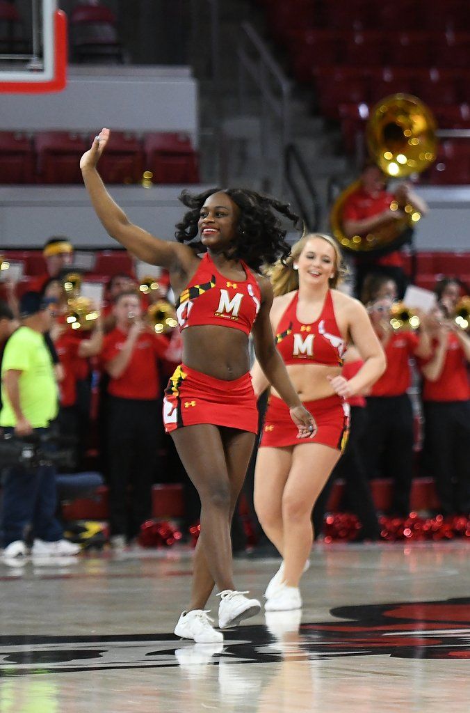 Two cheerleaders are dancing on a basketball court.