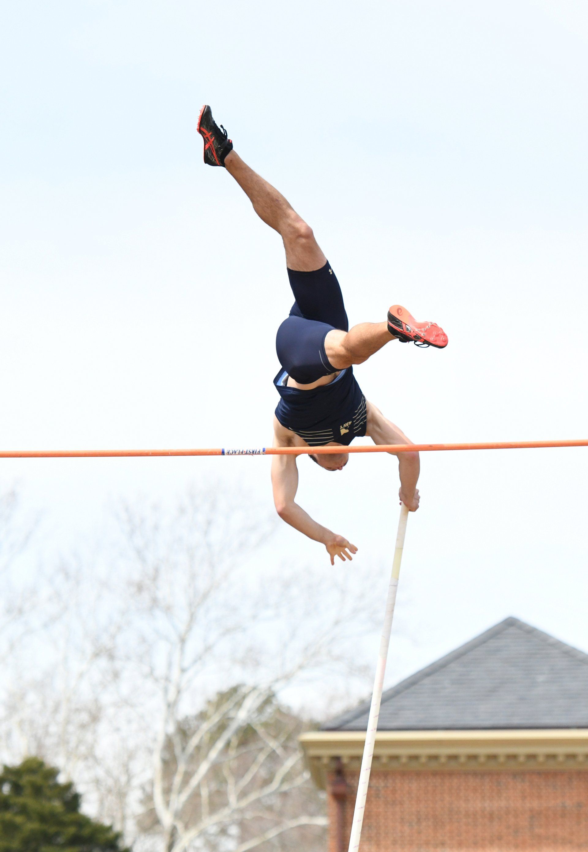 A person is doing a handstand over a pole