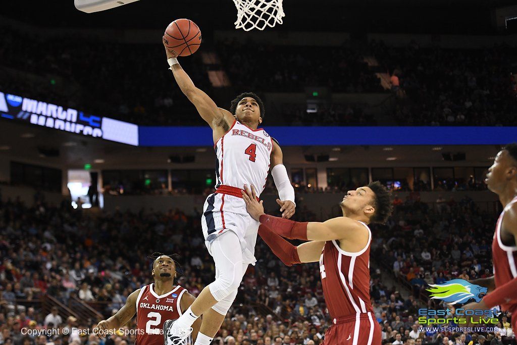 A basketball player is jumping in the air to dunk the ball.