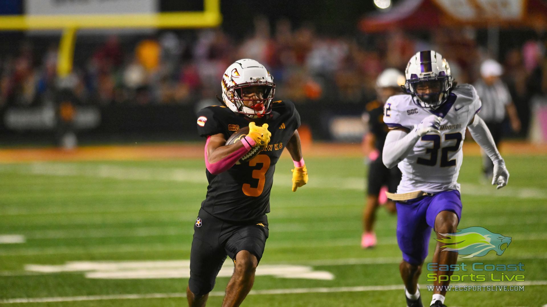 Two football players are running on the field during a game.