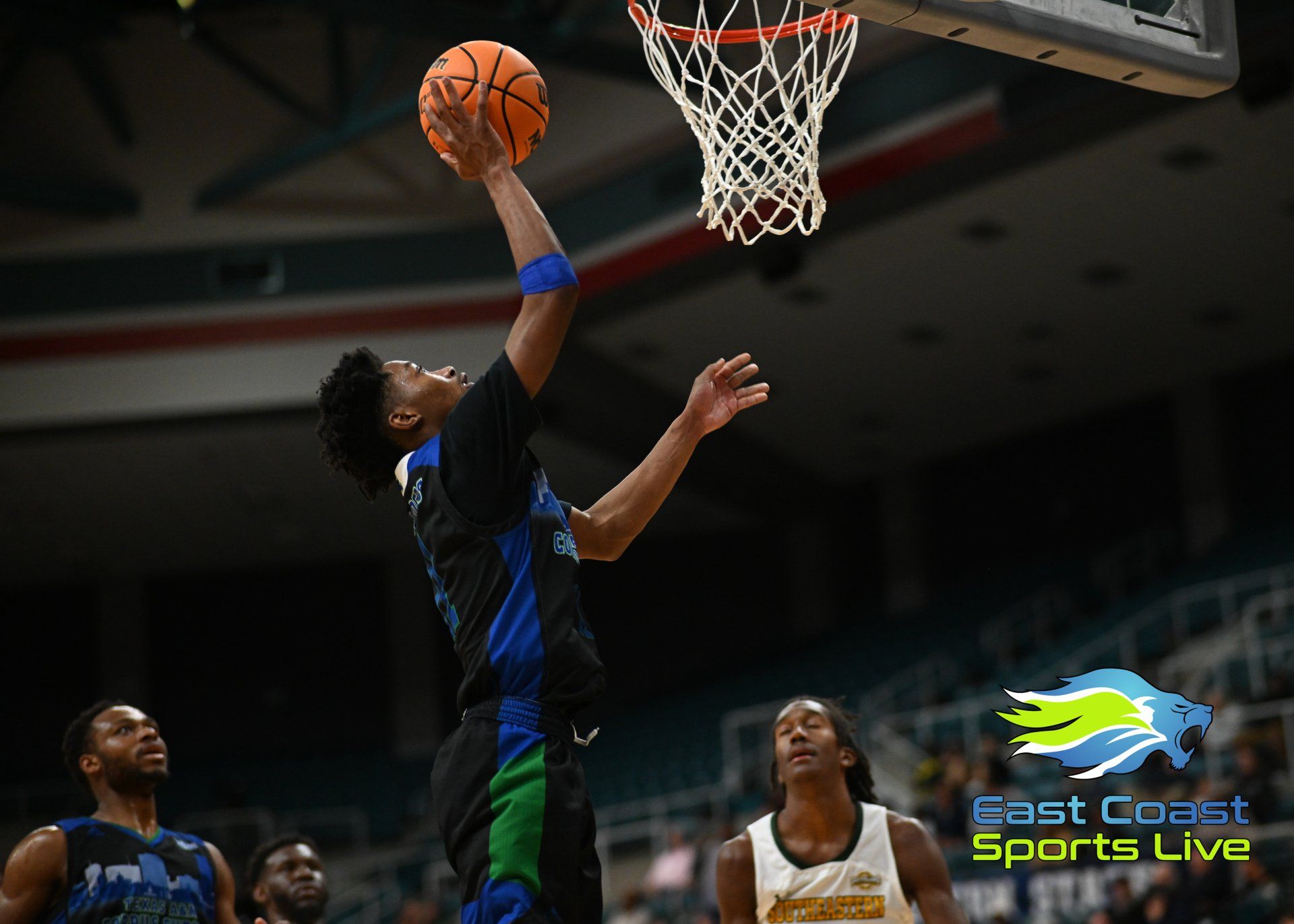 A basketball player is jumping in the air to dunk the ball