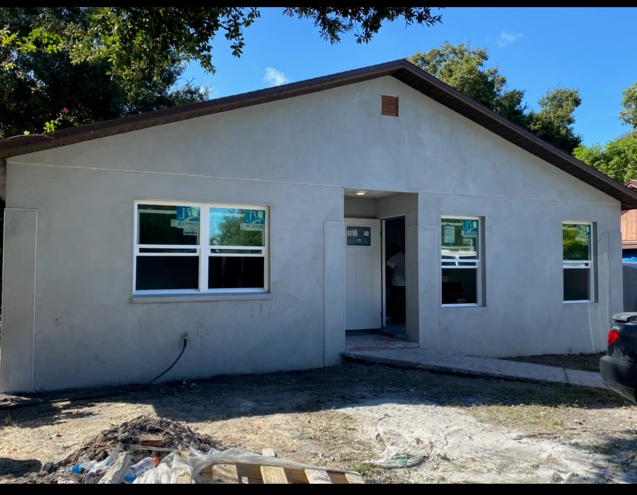 Newly constructed gray house with white trim, under blue sky.