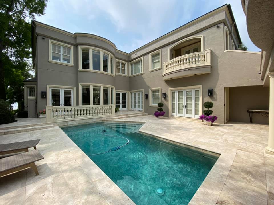 Luxury house with a swimming pool, gray exterior, two-story, with a balcony and arched windows.