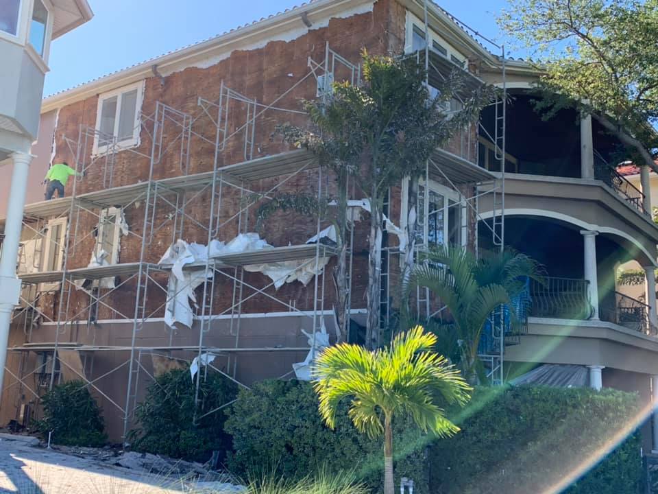 Construction workers on scaffolding, renovating a two-story house.