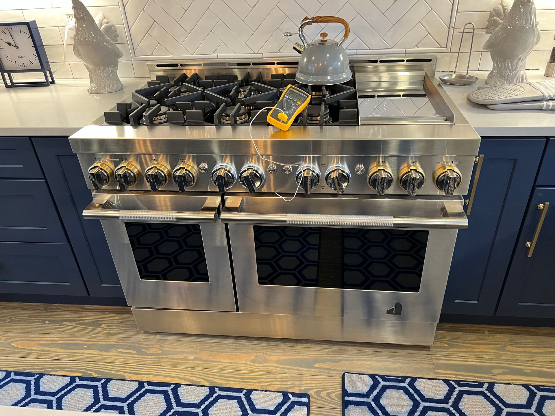 A stainless steel stove with a kettle on top of it in a kitchen.