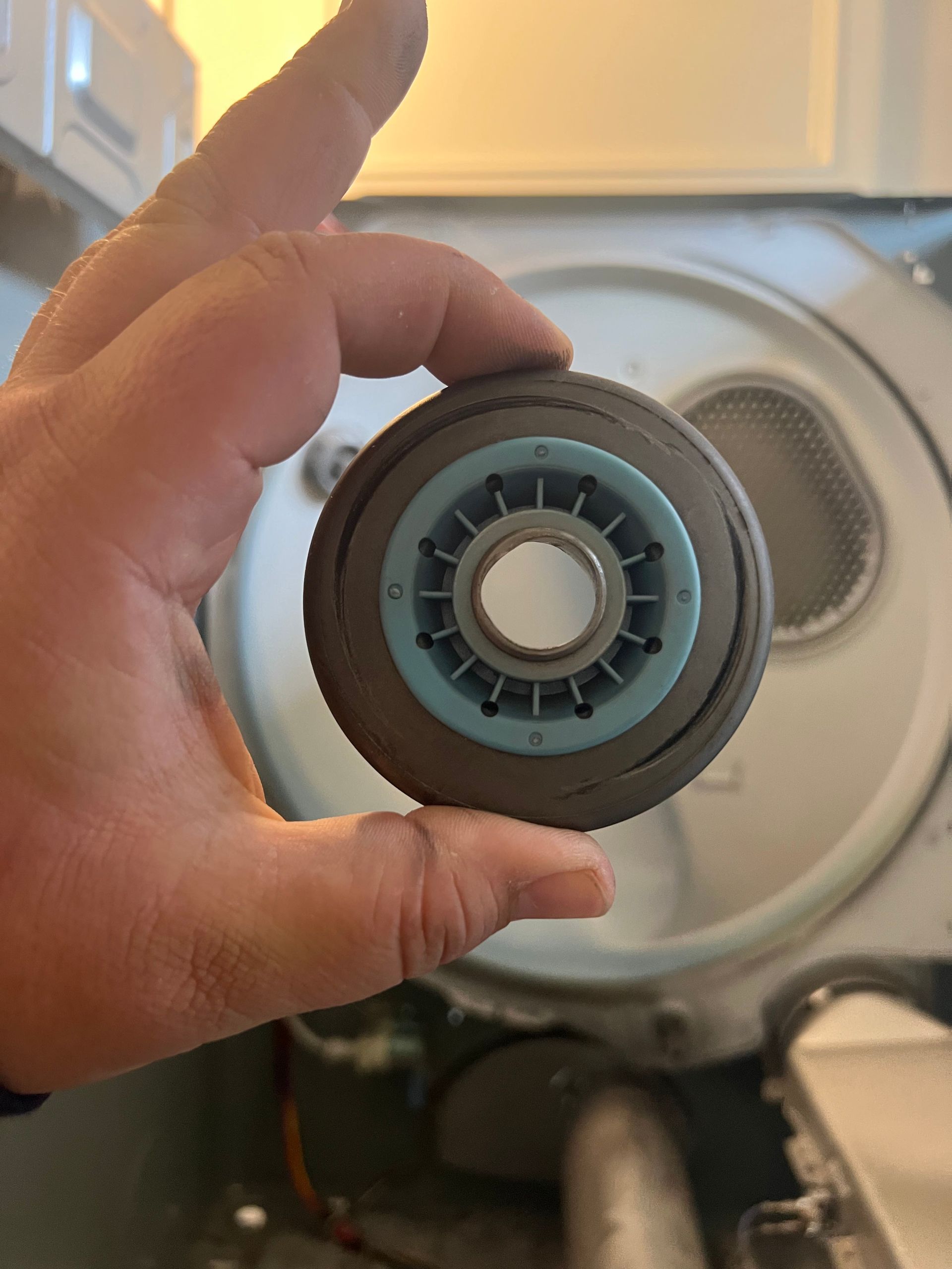 A person is holding a wheel in their hand in front of a washer and dryer.