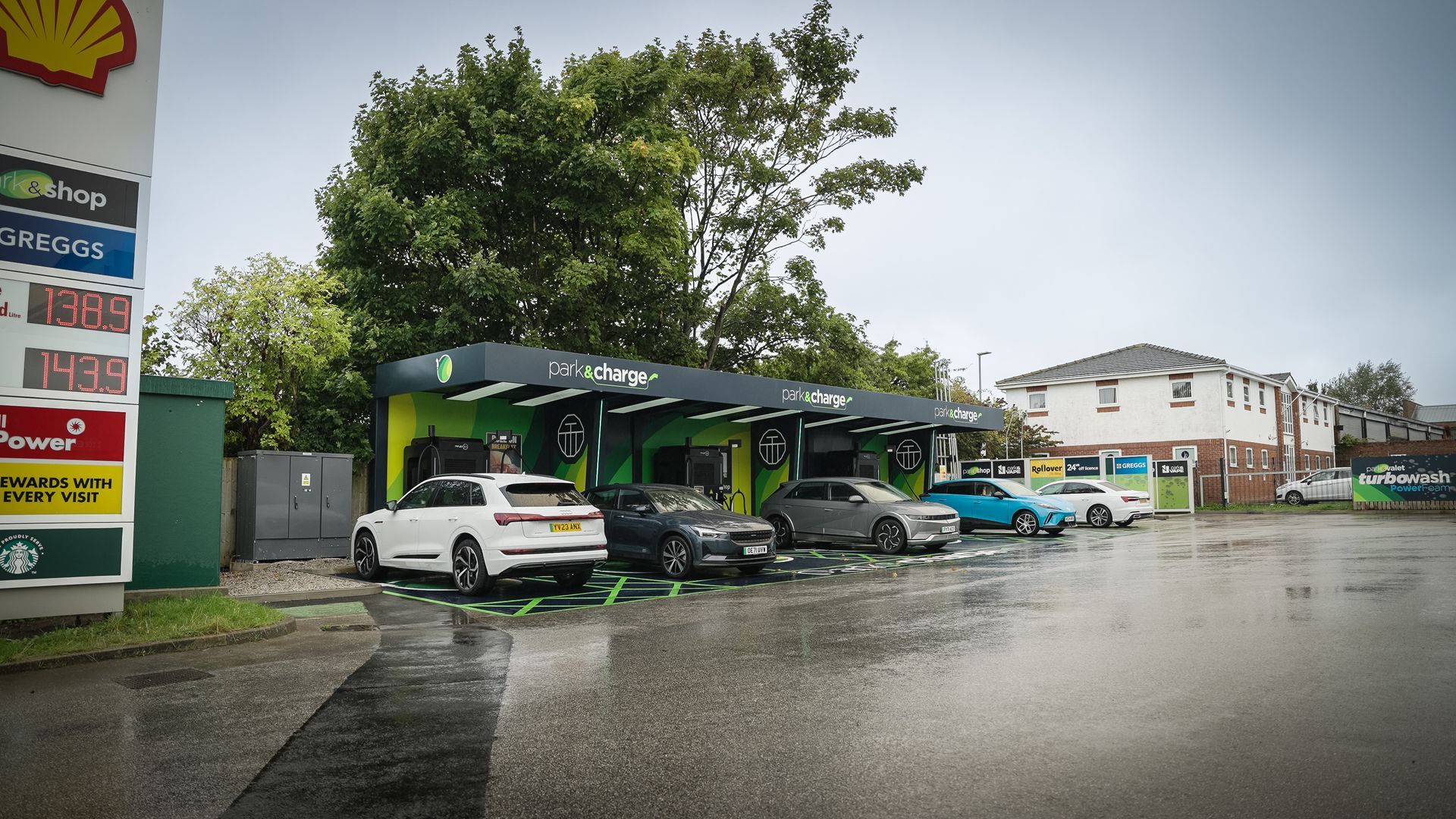 A row of cars are parked in front of a shell gas station.