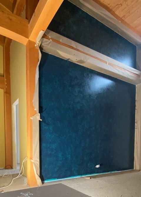 Blue panel or door framed in wood inside a partially finished attic or wall opening.