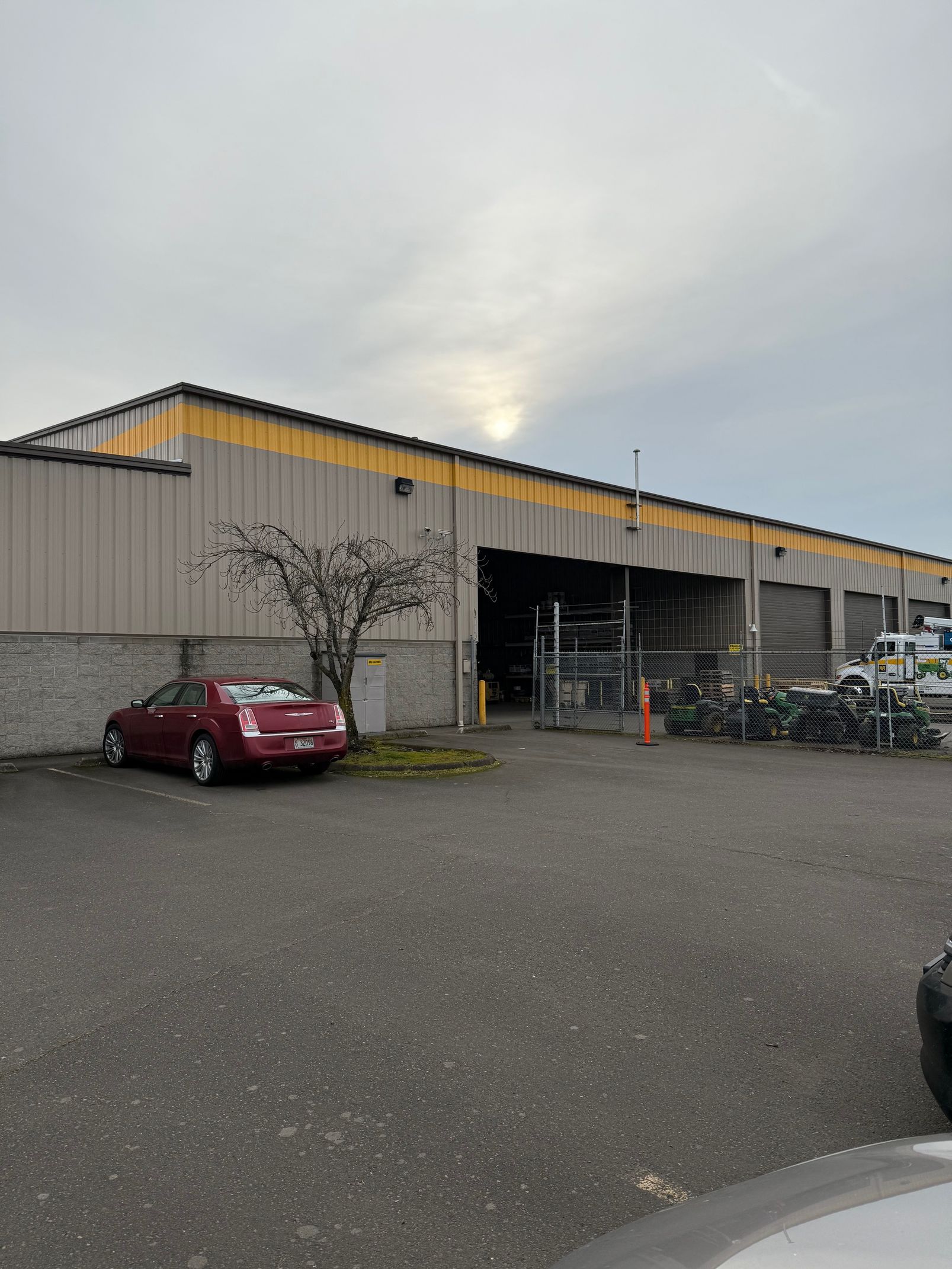 Industrial warehouse exterior with a red car parked outside and bicycles near the open loading area