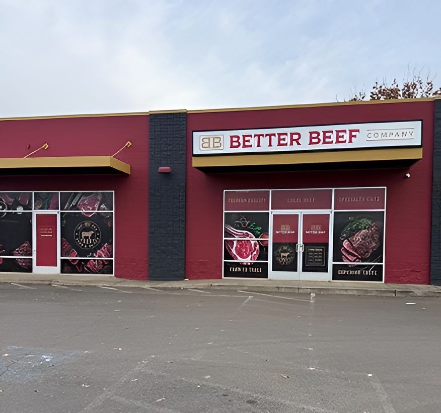 Storefront of Better Beef Company with red and black exterior and meat posters in the windows