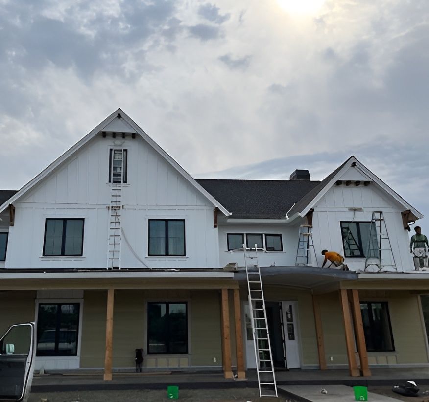 New white house exterior under construction with two ladders and workers on the front porch