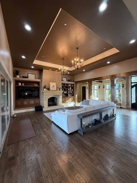 Elegant open-concept living room with coffered ceiling, fireplace, chandelier, and sectional sofa.