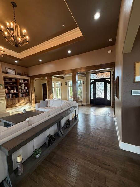 Spacious modern living room with beige sofas, wood floors, recessed lighting, and a view of the front entry.
