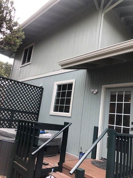 Apartment patio with black railing, gray siding, windows, and a lattice privacy screen.