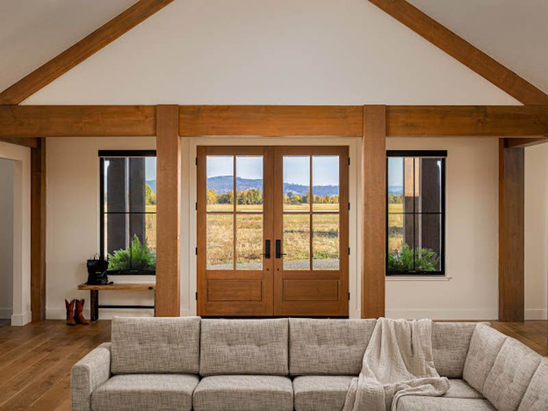 Living room with exposed beams, wood double doors, and mountain view through windows