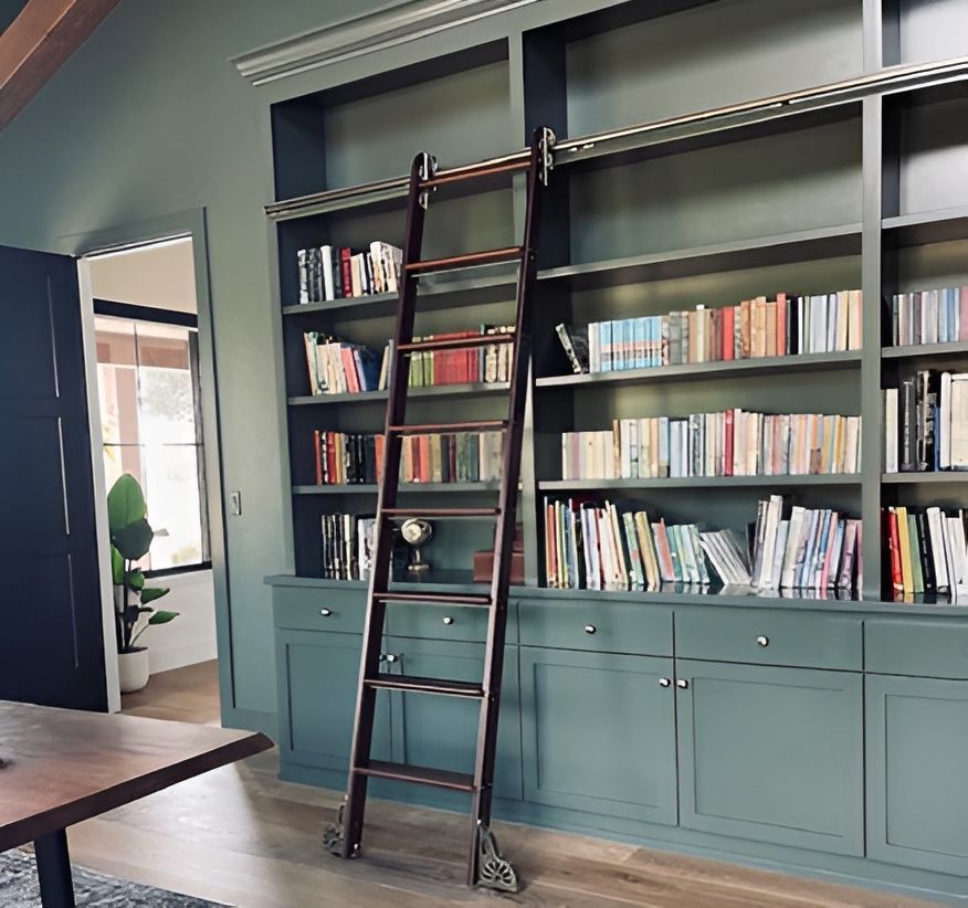 Teal built-in bookshelves with a dark wooden ladder in a modern room with books and cabinet storage.