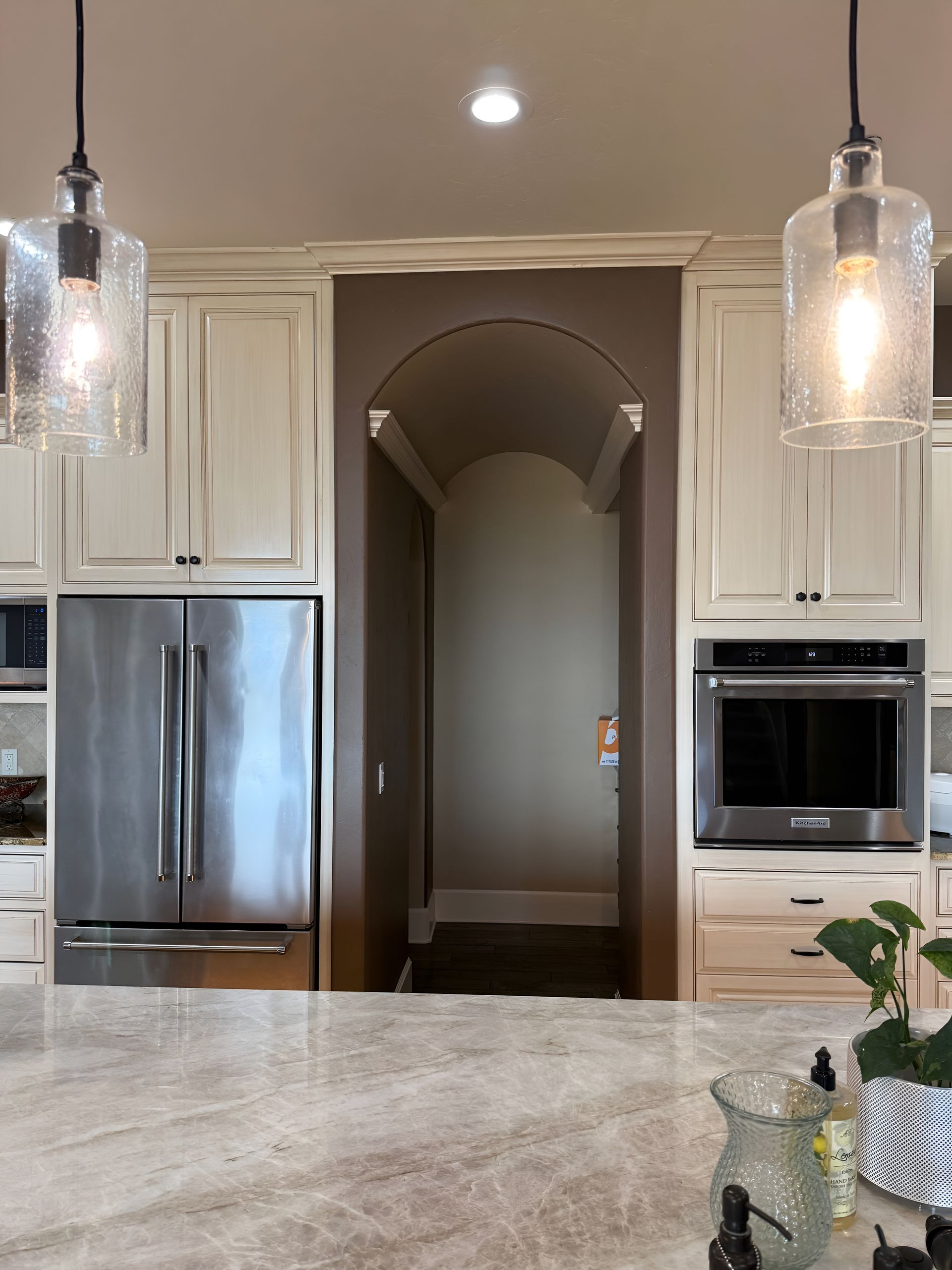 Modern kitchen with stainless steel fridge, white cabinets, double ovens, and pendant lights