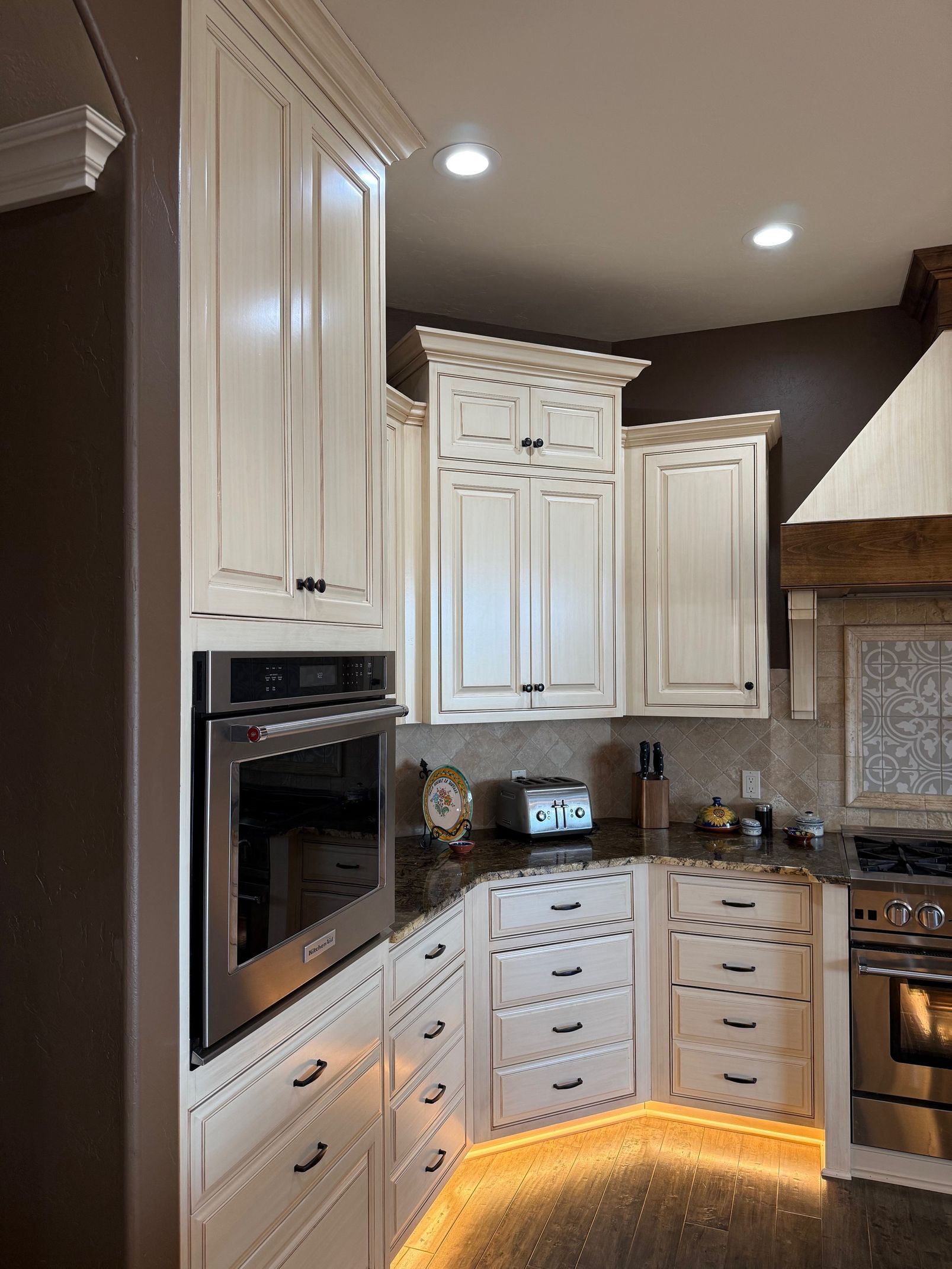 Modern white kitchen with built-in oven, granite counters, and under-cabinet lighting