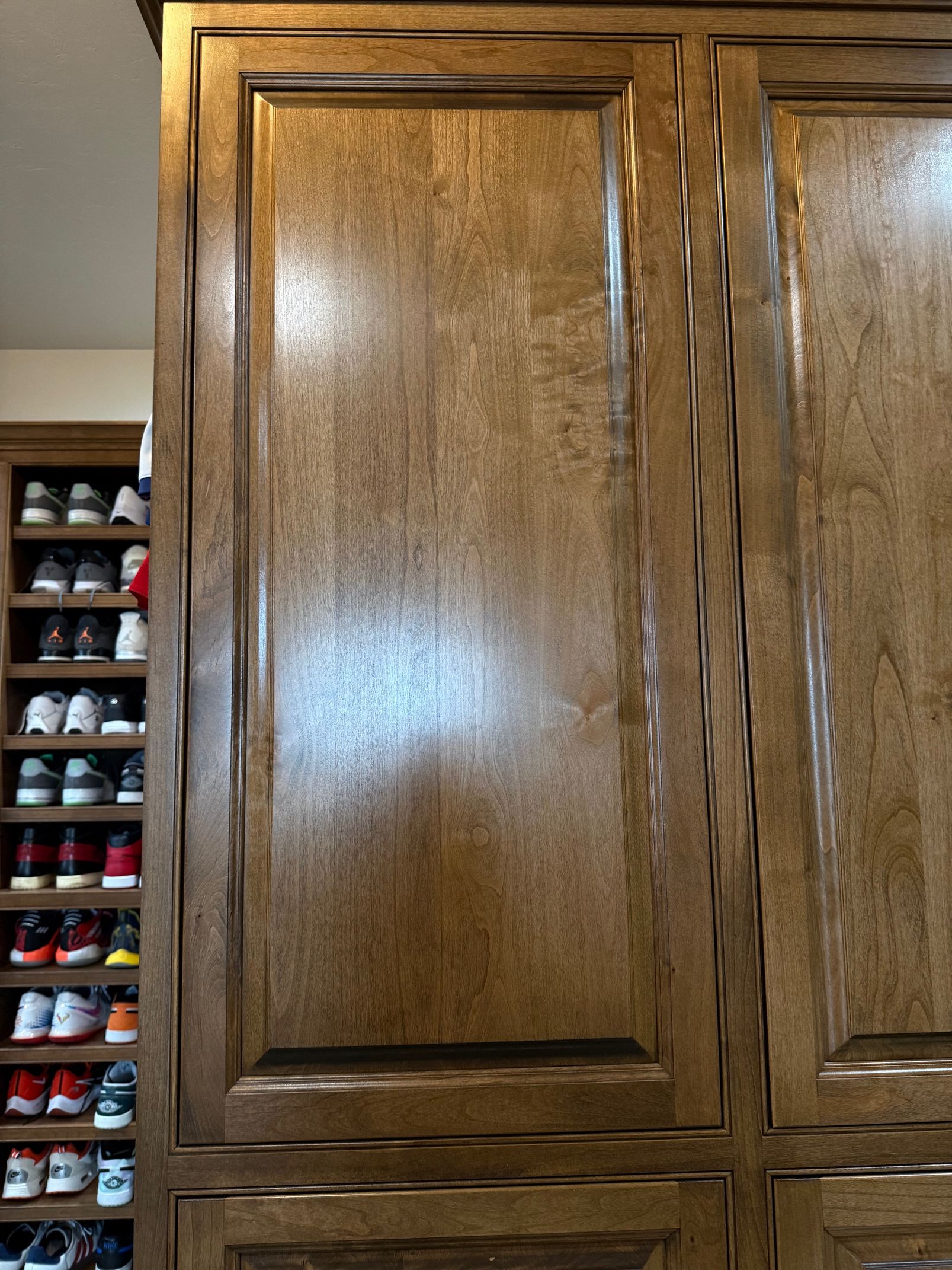Wooden cabinets and a narrow shoe rack filled with shoes along the left side.