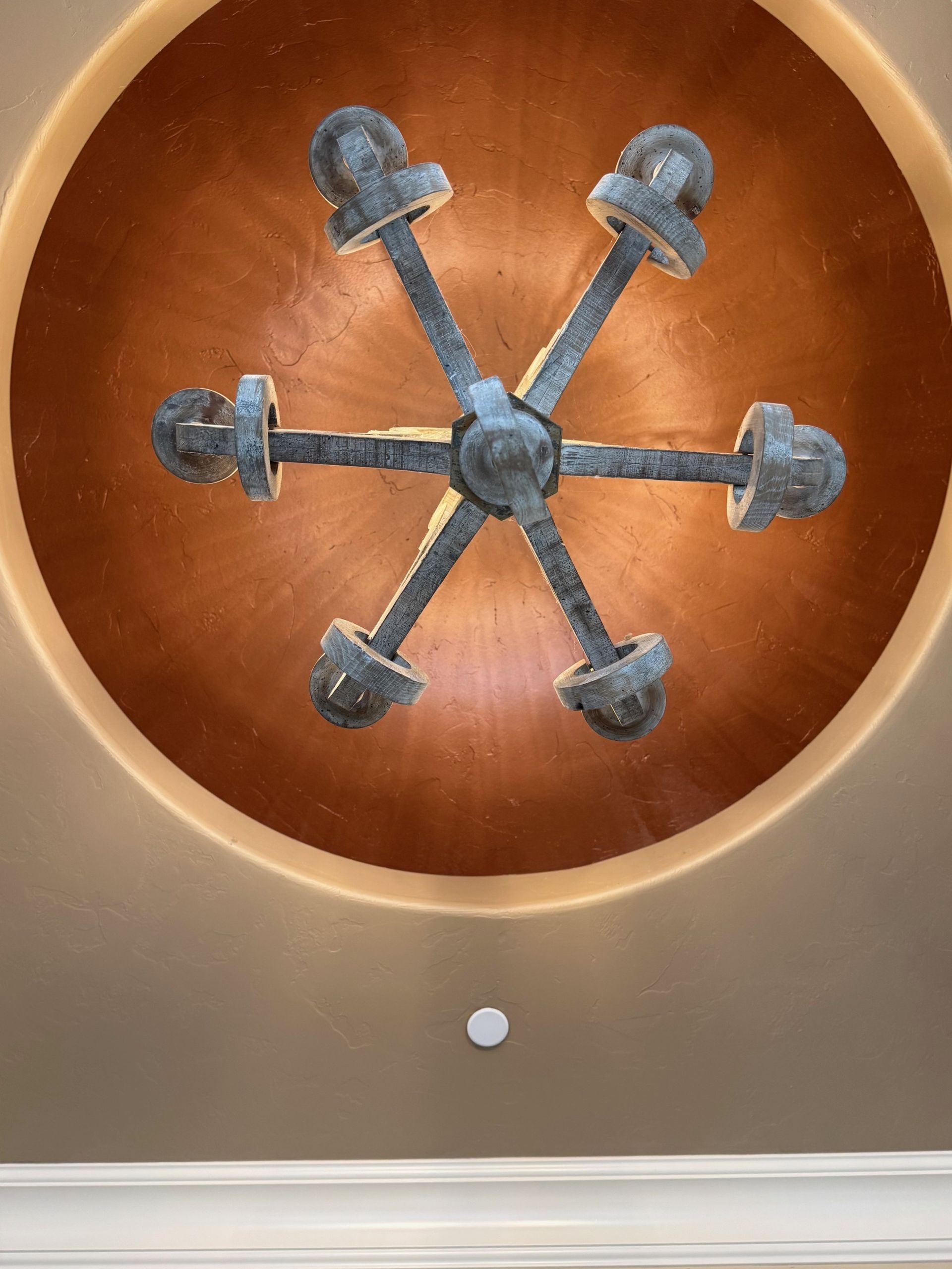 Circular ceiling light fixture with six exposed bulbs on a tan ceiling
