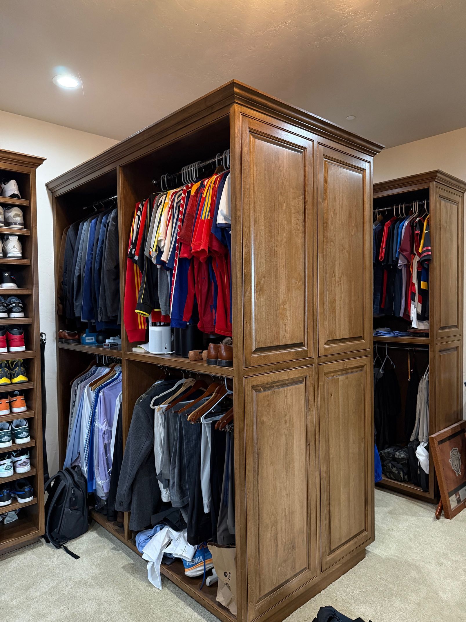 Wooden closet island with hanging clothes in a bedroom walk-in closet