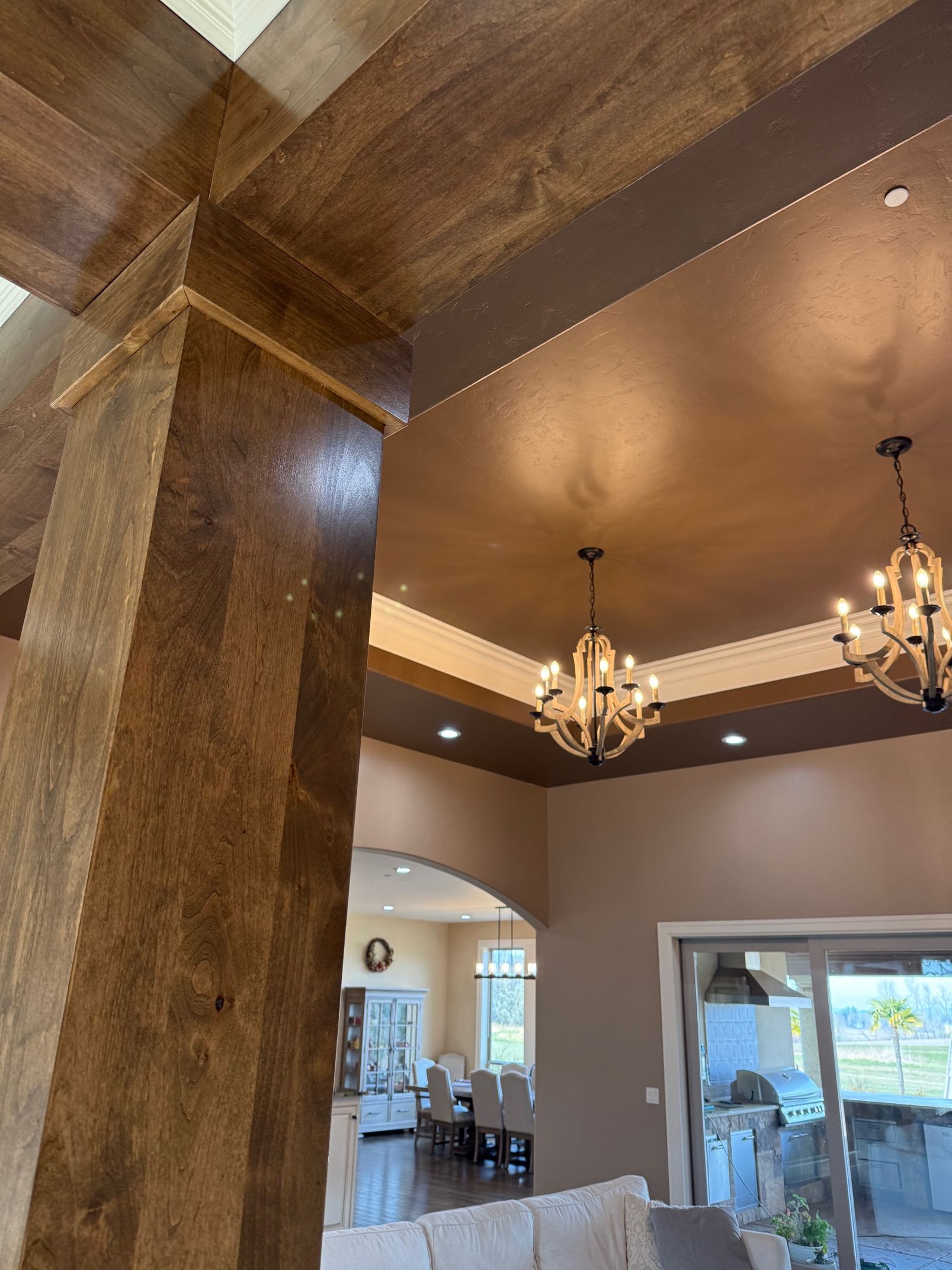 Interior with textured columns, recessed lighting, and chandeliers in a spacious entryway