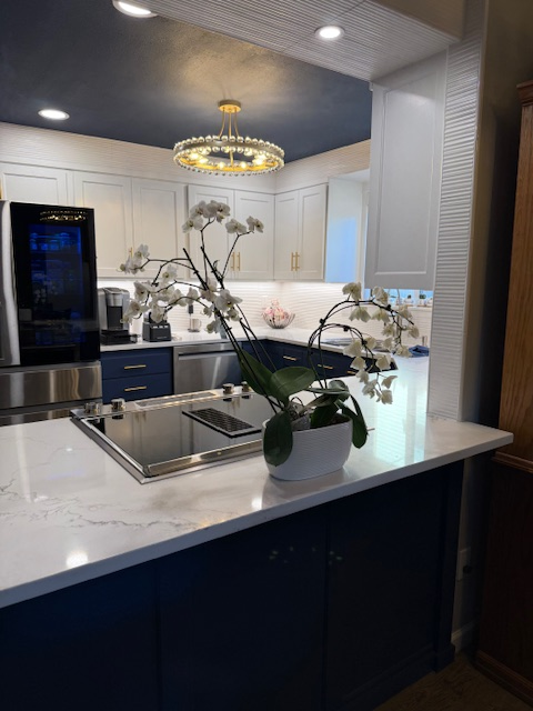 Modern kitchen with marble island, dark cabinets, stainless appliances, and orchid centerpiece