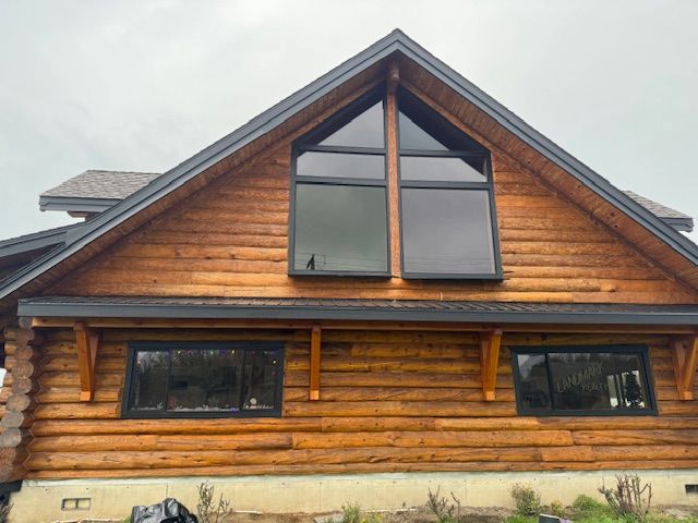 Rustic log cabin exterior with a steep gabled roof and large central windows
