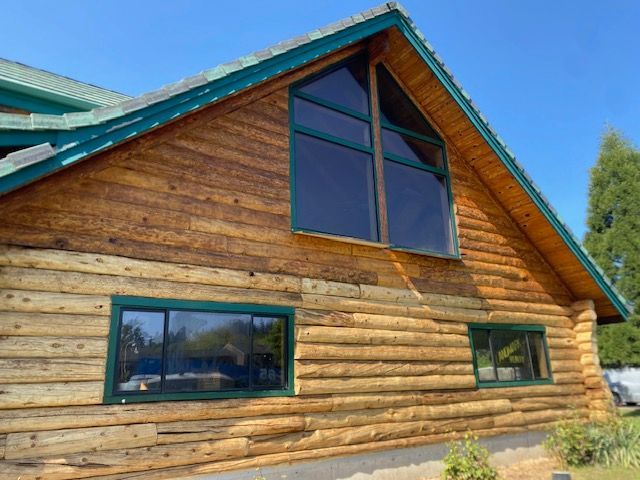 Wooden log cabin with blue-trimmed gable and windows under a clear sky