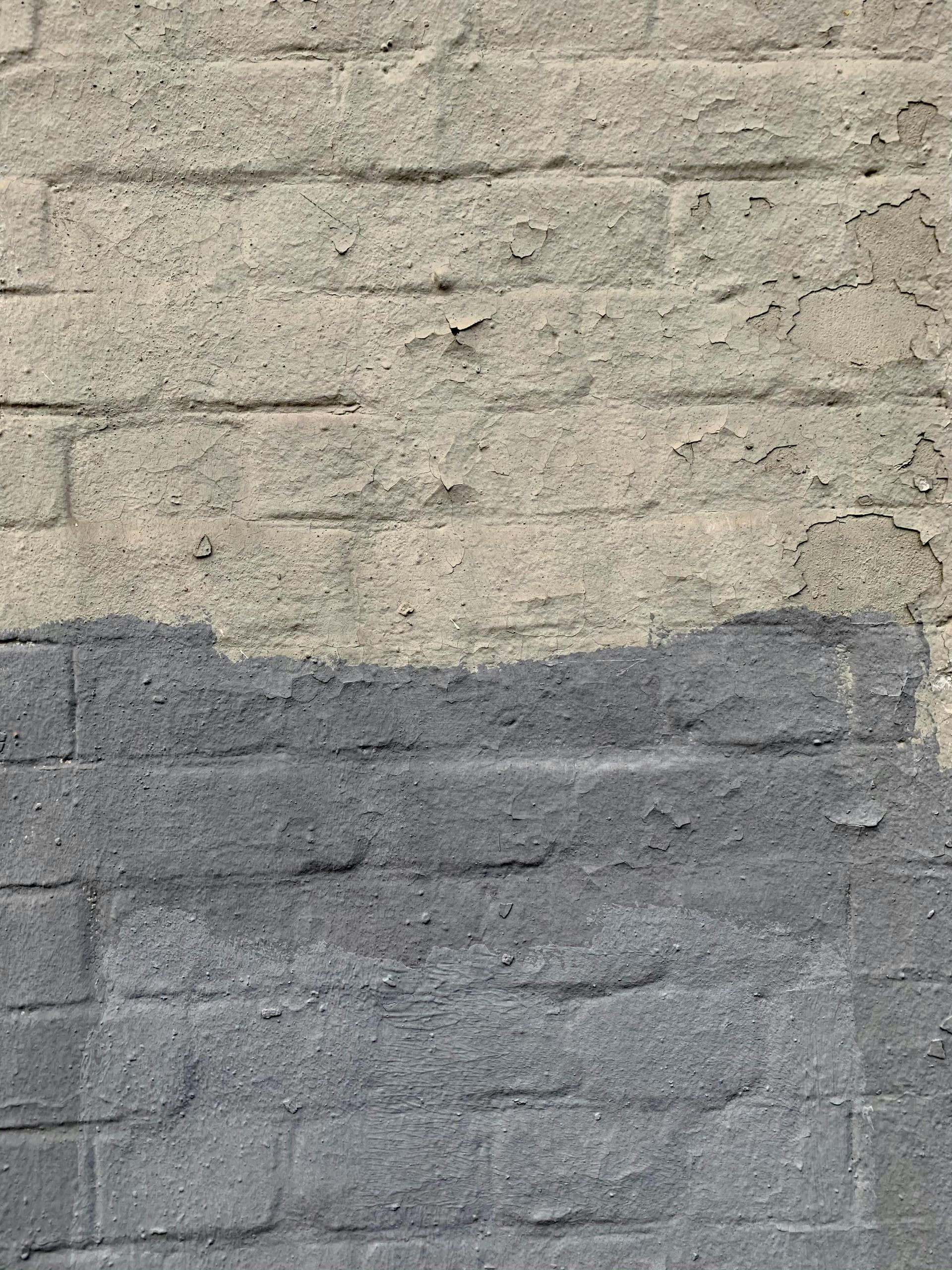 Two-tone painted brick wall, light beige above and dark gray below.