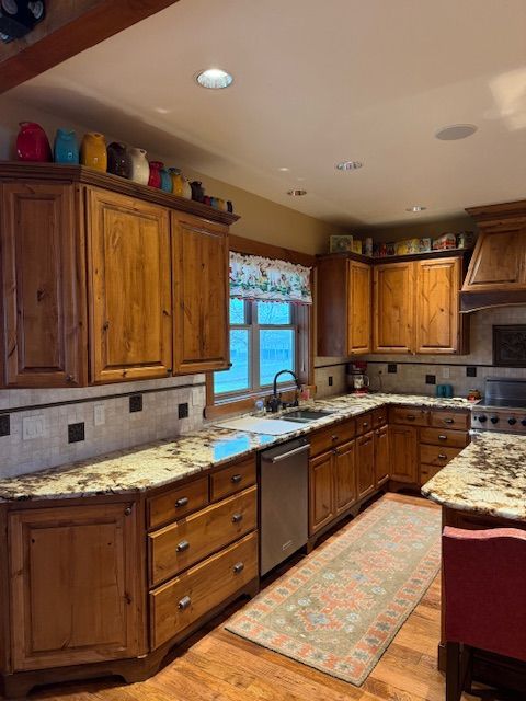 Wooden kitchen with granite counters, tiled backsplash, and a window over the sink.