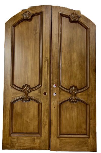 Ornate double wooden front doors with arched top and decorative carved panels