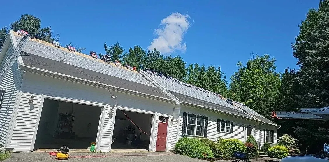 A white house with a roof that is being remodeled.