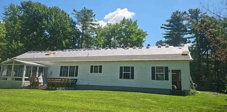 A white house is sitting in the middle of a lush green field.