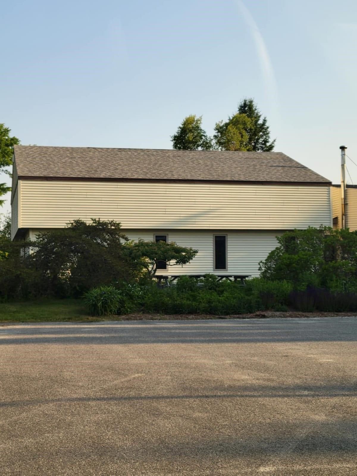 A white house with a gray roof and a rainbow in the sky